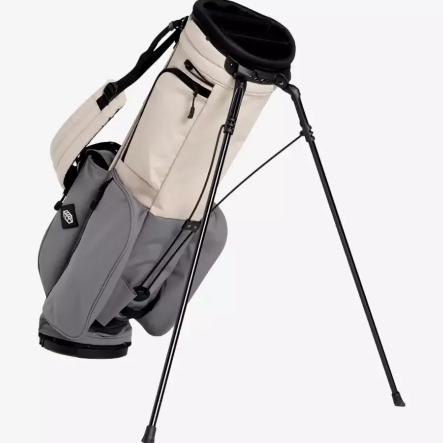 A beige and gray golf stand bag, one of the best golf bags 2026, features multiple pockets and sturdy black legs extended for support, shown against a plain white background.