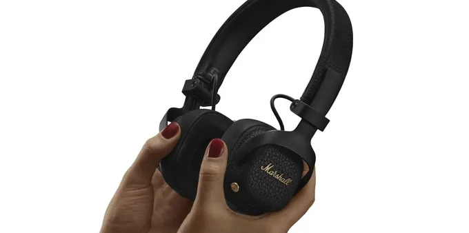 A person holding Marshall Milton A.N.C. headphones against a white background