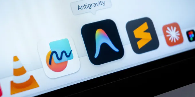 laptop screen displays the macOS Dock featuring Google Antigravity extension, and VLC media player.
