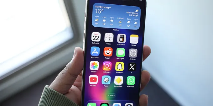 Person holding an iPhone displaying the home screen