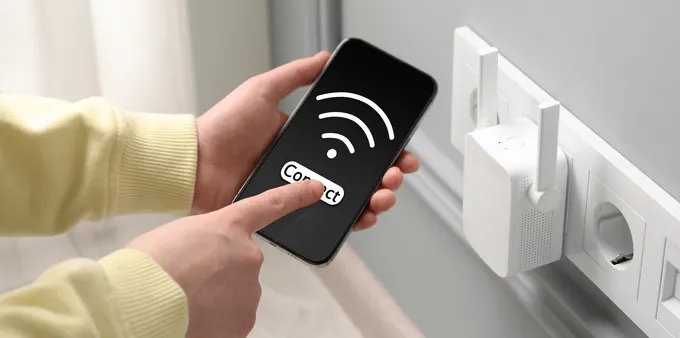 Wi-Fi extender plugged into an outlet and a person checking phone signal.