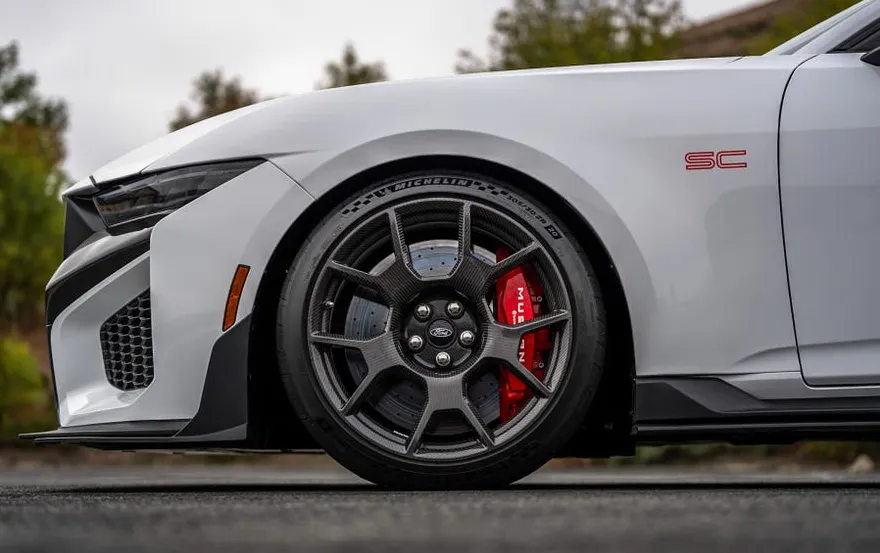 Close-up of a sports car's front wheel showcasing a sleek design and red brake calipers.