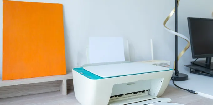 Printer on desk next to a Wi-Fi router and other equipment.